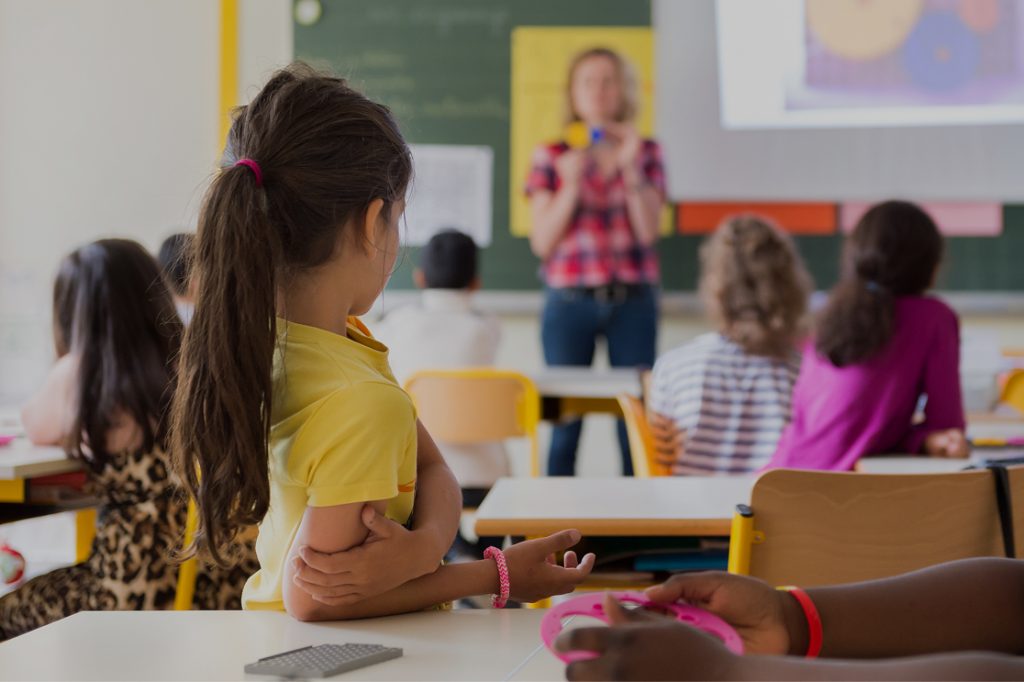 Petit fille seule au fond de la classe de l'école devant sa maitresse